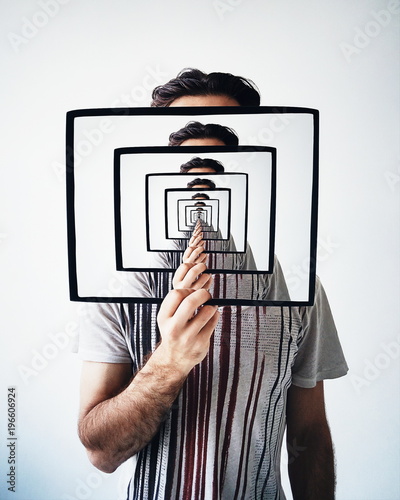 Young man holding frame with recursion effect. Creative concept photo