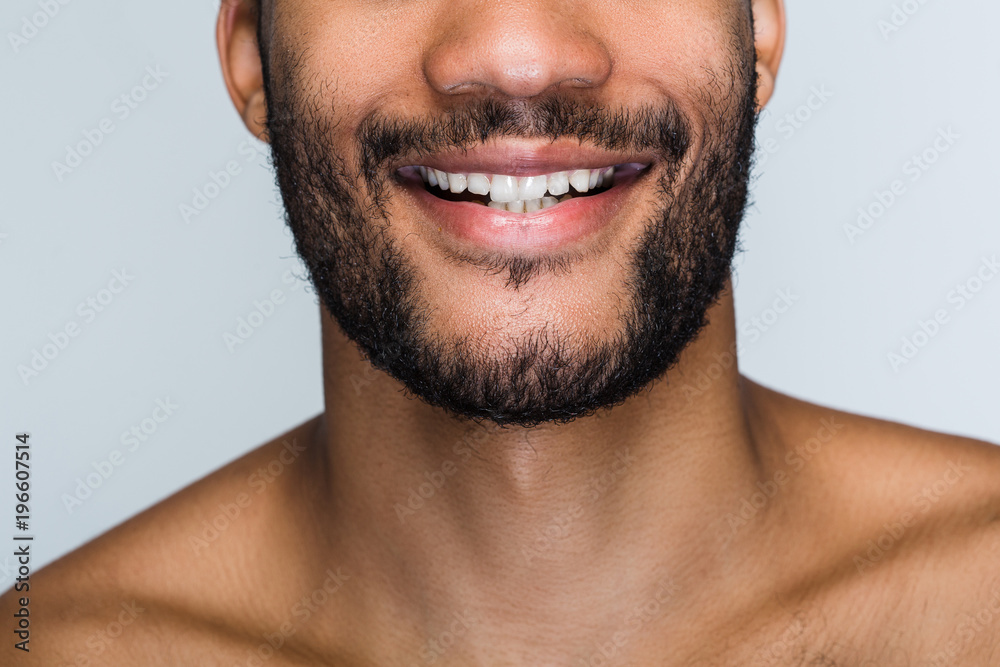 Fototapeta premium Cheerful smile. Close up part of handsome young black man smiling while standing against white background