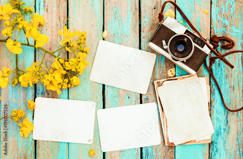 Retro camera and empty old instant paper photo album on wood table with flowe...