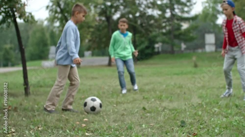 Group of primary school boys warming up with football before game in park during school recess