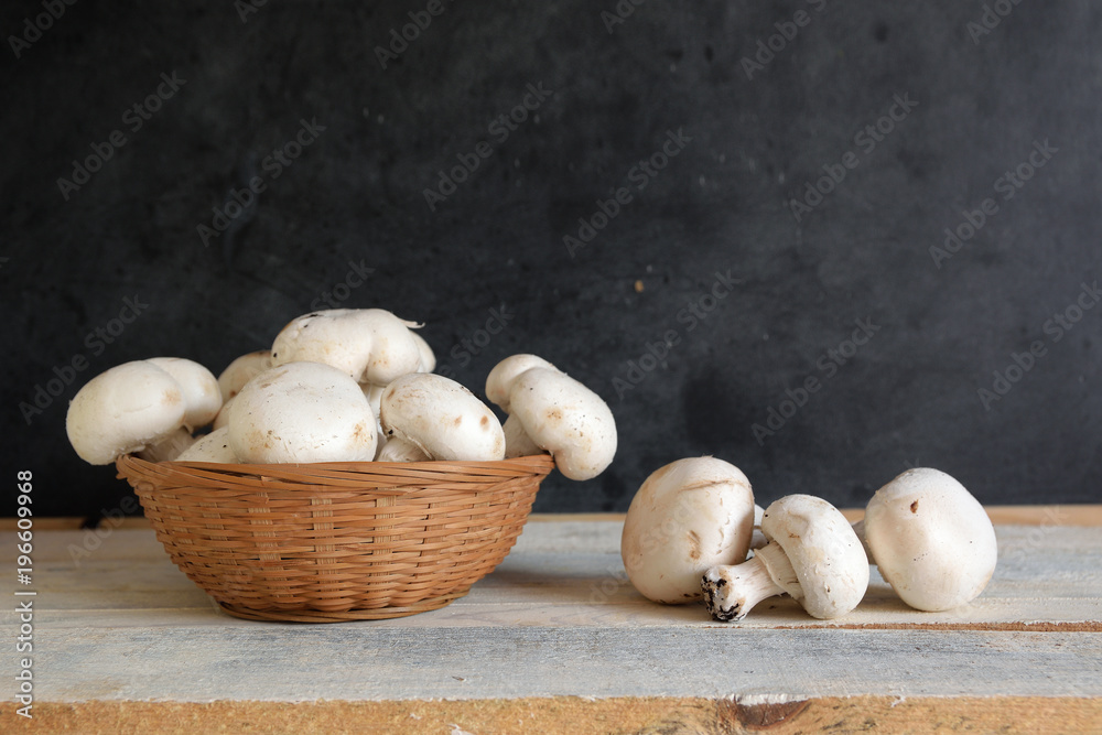 Some natural mushrooms in a basket on a white wooden table in a rustic kitchen. Empty copy space for Editor's text. Some natural mushrooms in a basket on a white wooden table in a rustic kitchen. Empty copy space for Editor's text.