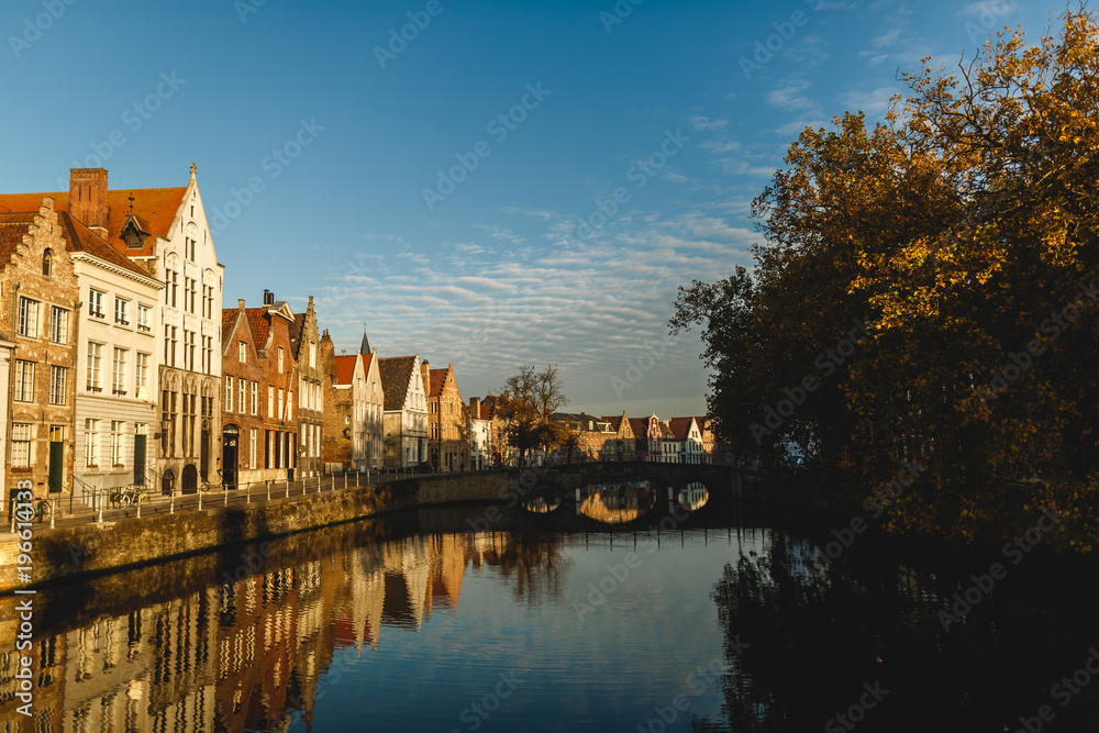 beautiful traditional houses reflected in calm water of canal, brugge, belgium