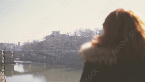 alone and melancholy woman observes the river photo