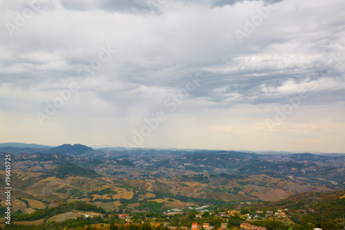 Panoramic view of San Marino. Green valley with orange roofs houses. Cloudly sky in summer. © Nataliia