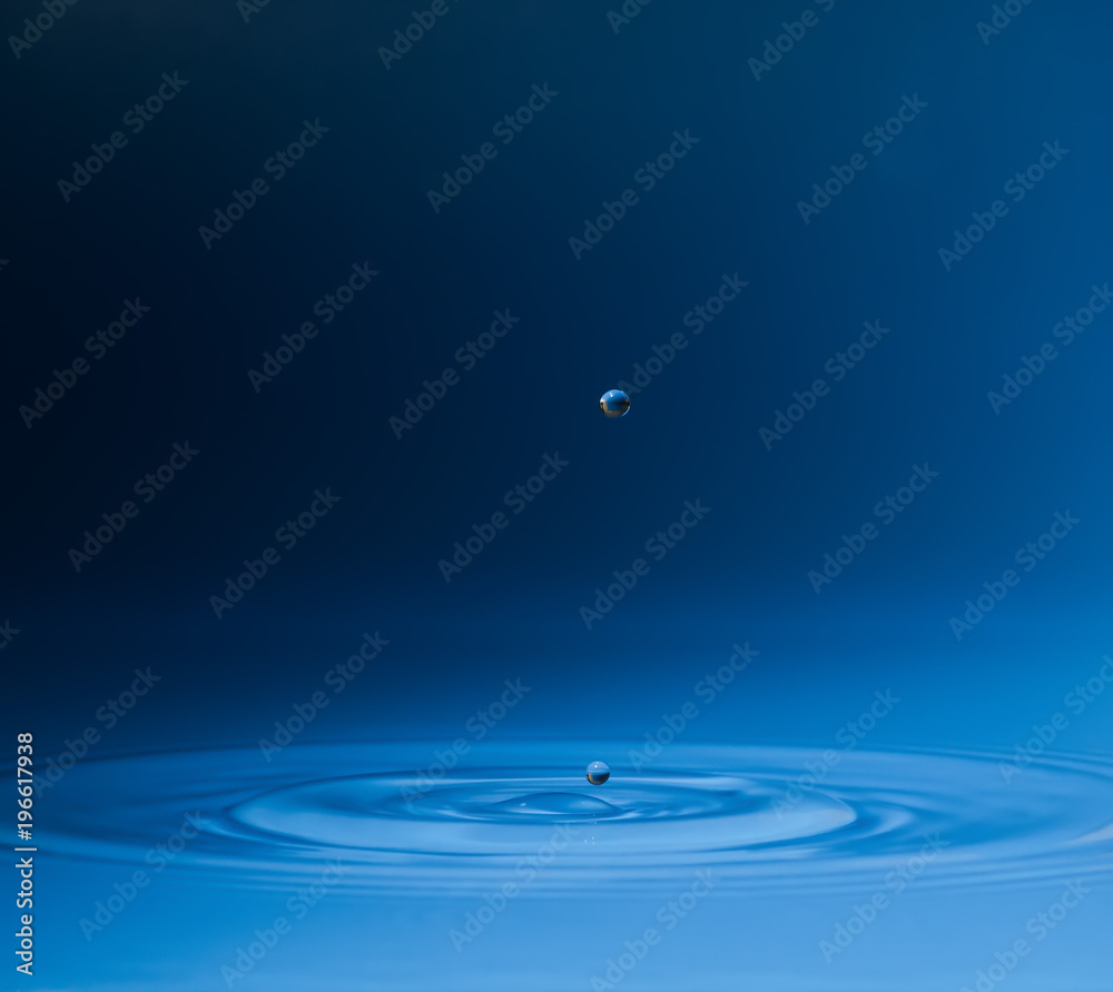 drop of water liquid with splash isolated. the drop explodes in the water sending spray to the sides and circle ripples around it. the water is blue drop of water liquid with splash isolated. the drop explodes in the water sending spray to the sides and circle ripples around it. the water is blue