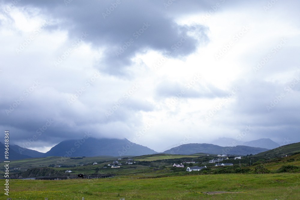 Nature meadow panorama with the small village before the rain in Ireland