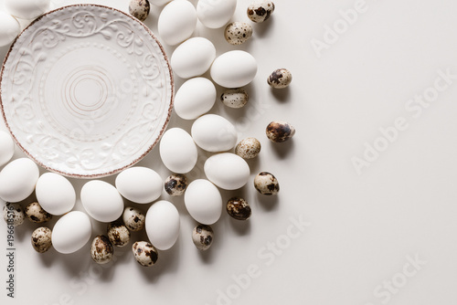 food composition with chicken and quail eggs around plate on white