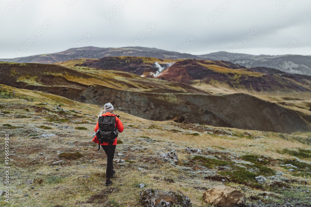 One woman wanders in Iceland with backpack in a red jacket One woman wanders in Iceland with backpack in a red jacket