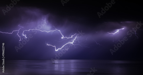 lightning bolts reflection over the sea. taken during a thunderstorm over the ocean with clouds in the background