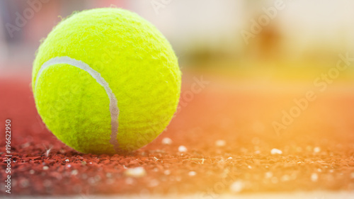 Sport Item concept : Tennis balls at red court in summer day. Tennis is racket sport that can be played individually against single opponent (singles) or between two teams of two players each. © smolaw11