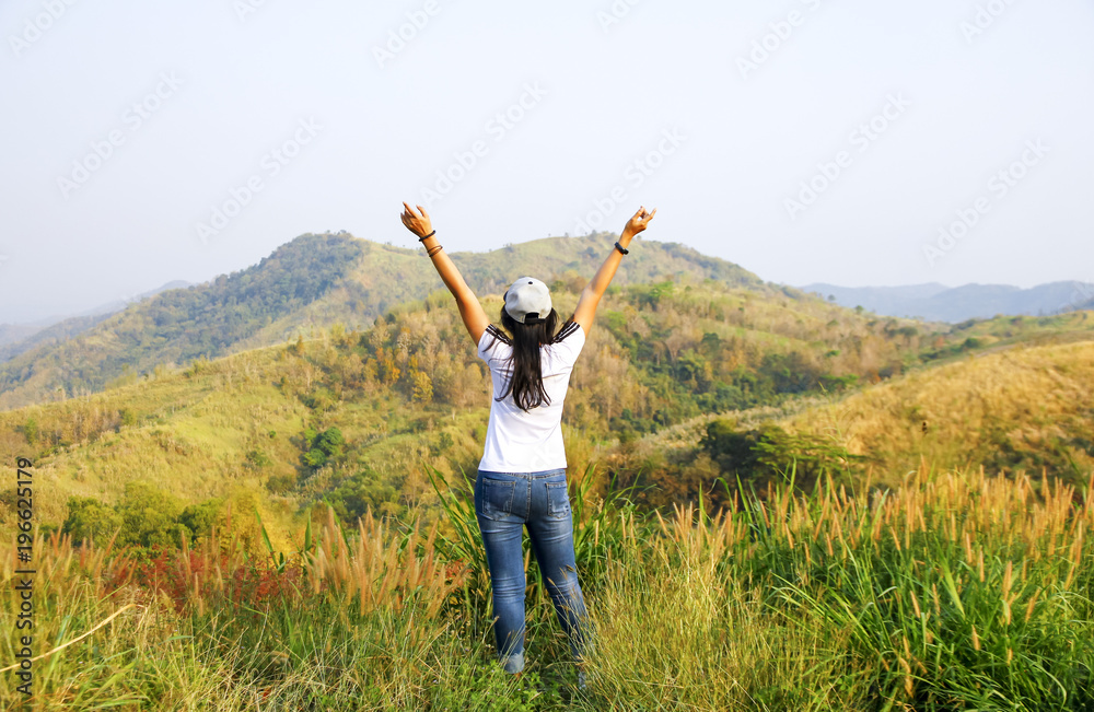 Young woman standing on cliff's edge and looking into a wide valley Young woman standing on cliff's edge and looking into a wide valley