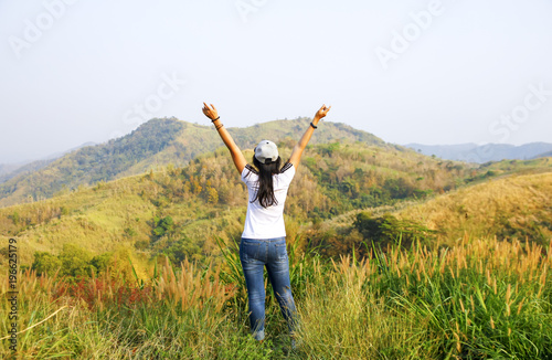 Young woman standing on cliff's edge and looking into a wide valley