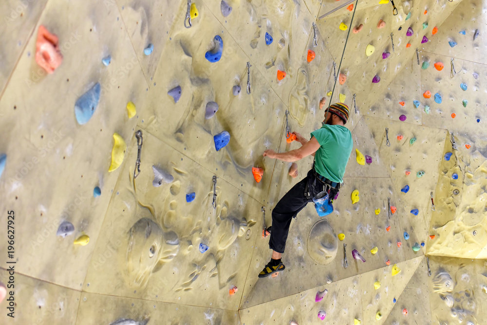 klettern in einer Kletterhalle - Mann klettert an einer Wand mit Sicherung hoch
