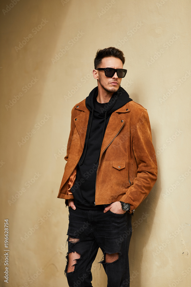 Model looking man stand near the wall and hold his glasses towards the sun shine Model looking man stand near the wall and hold his glasses towards the sun shine