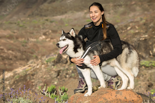 Beautiful woman embracing dog on rocks