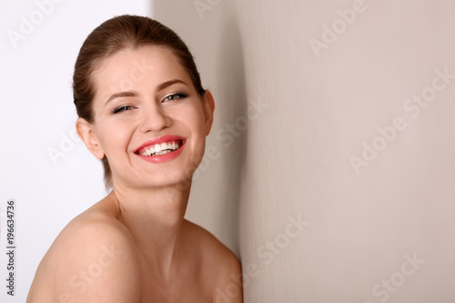 Portrait of beautiful young woman with soft skin after applying cream on light background