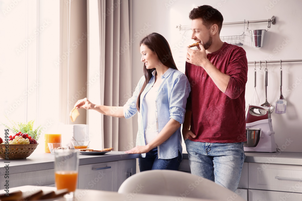 Young couple having breakfast with toasts in kitchen