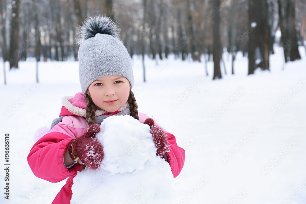 Cute girl making snowman in park on winter vacation Cute girl making snowman in park on winter vacation