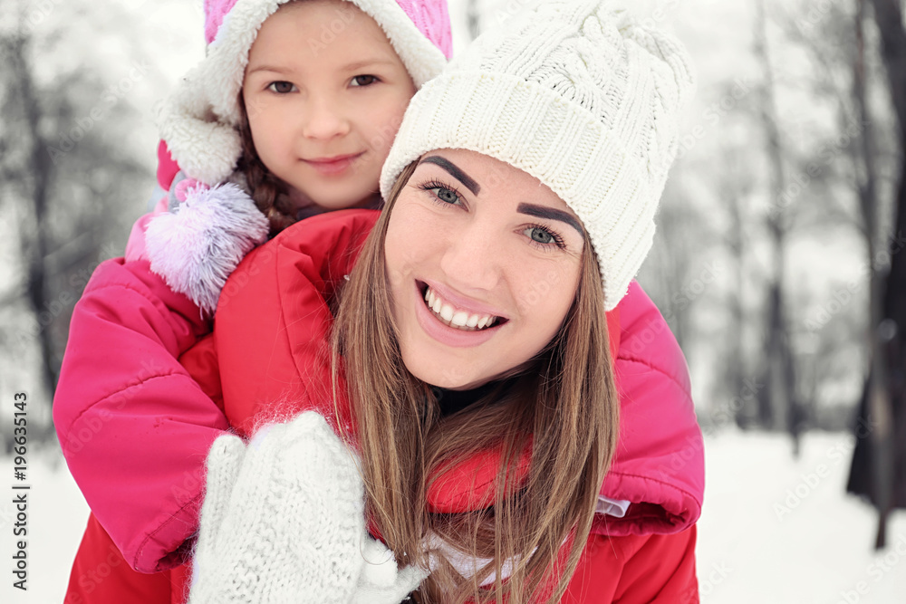 Happy woman with daughter in snowy park on winter vacation