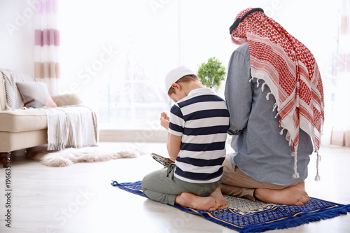 Muslim man praying with son...