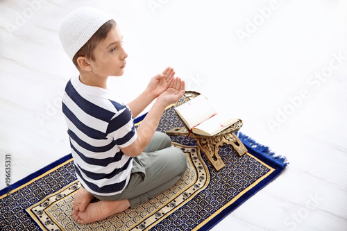 Muslim boy praying on rug a...