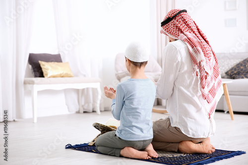 Canvas Print Muslim man praying with son at home