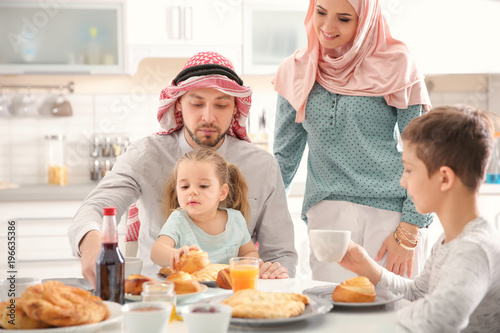 Happy Muslim family having breakfast together at home
