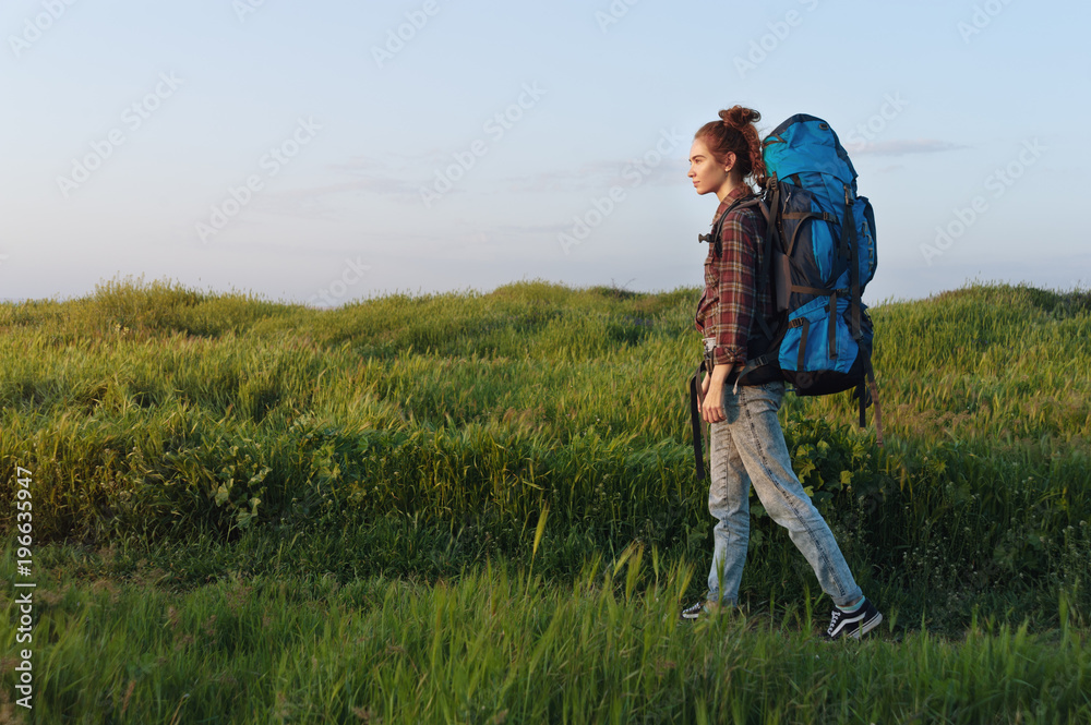 Hiker girl is traveling with a backpack on the landscape background Hiker girl is traveling with a backpack on the landscape background