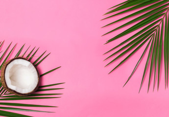 Palm leaves and half of coconut on the pink background