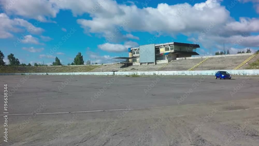 Car driving on race circle on abandoned autodrome with blue sky background Car driving on race circle on abandoned autodrome with blue sky background