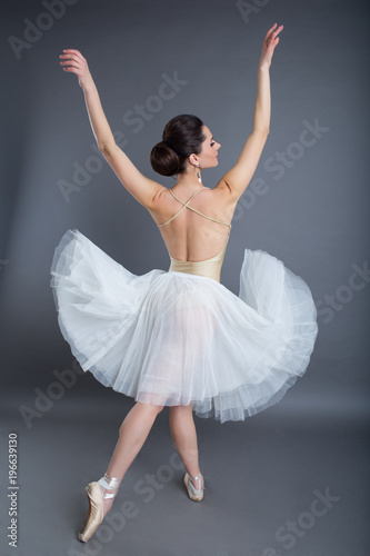 Beautiful slim sexy woman ballet dancer in studio isolated on gray