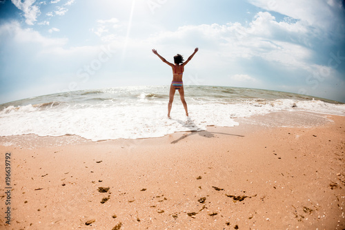 A girl is jumping on the beach.