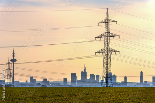 Big cities are supplied with electricity via power lines. Here in the foreground high-voltage power lines and in the background the city of Frankfurt am Main. Concept: energy supply