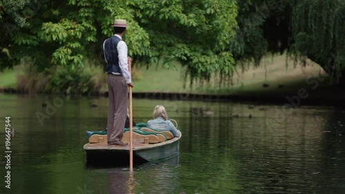 Mid shot punting down a tranquil river under a willow tree.