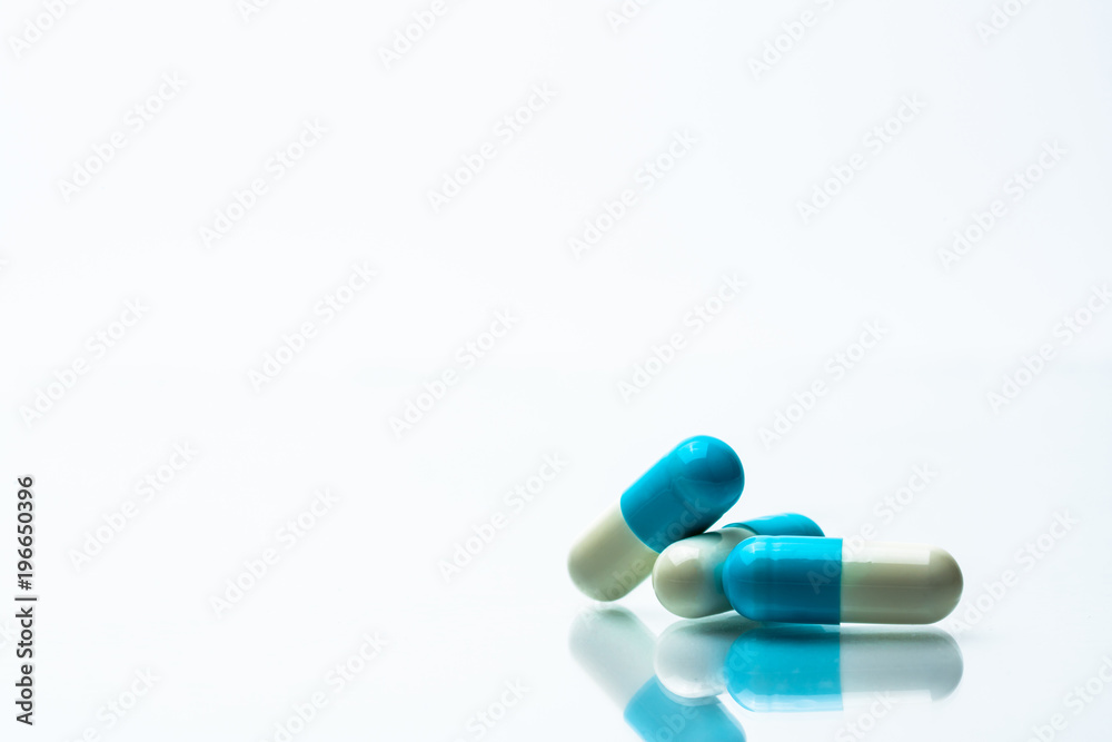 Three blue and white capsules pills on white background with shadows and copy space for text. Three blue and white capsules pills on white background with shadows and copy space for text.