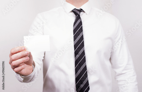 Business man holds a business card with one hand. Business