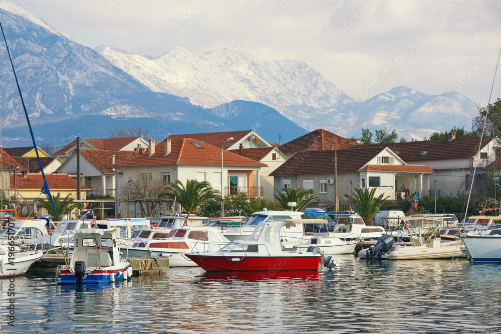 Small green town at the foot of the snowy mountains. Montenegro, view of Tivat city and snow-capped peaks of Lovcen