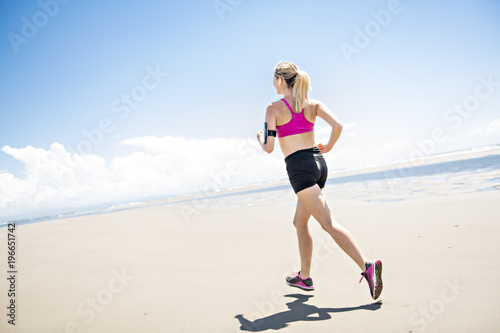 Young woman jogging on the beach in summer day. Athlete runner exercising actively in sunny day