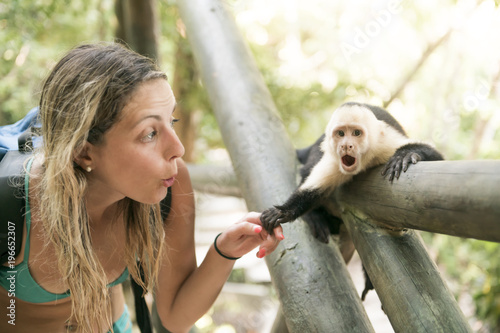 Canvas Print curious monkey holding woman hand in forest