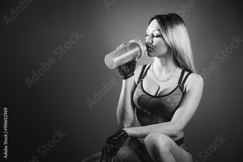 Pretty caucasian fitness girl on diet resting after exercise And drinking protein powder from shaker in the gym photo