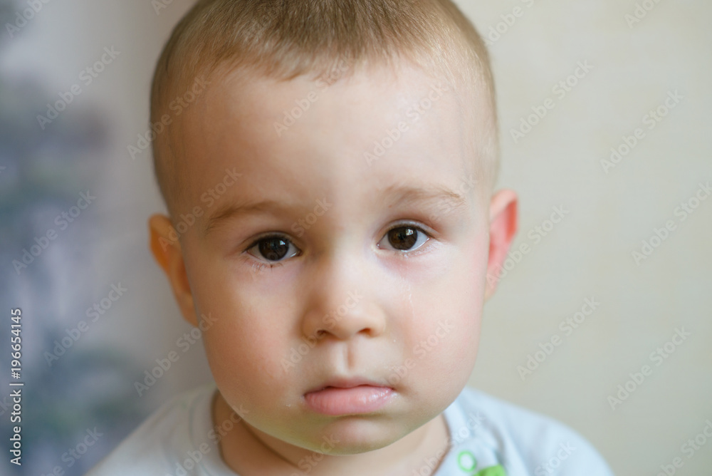 Sad little baby boy looking at camera. Caucasian child 2 years old. Closeup portriat.