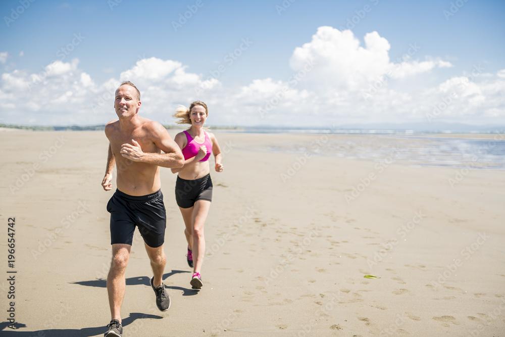 Fitness running couple exercising cardio on beach.