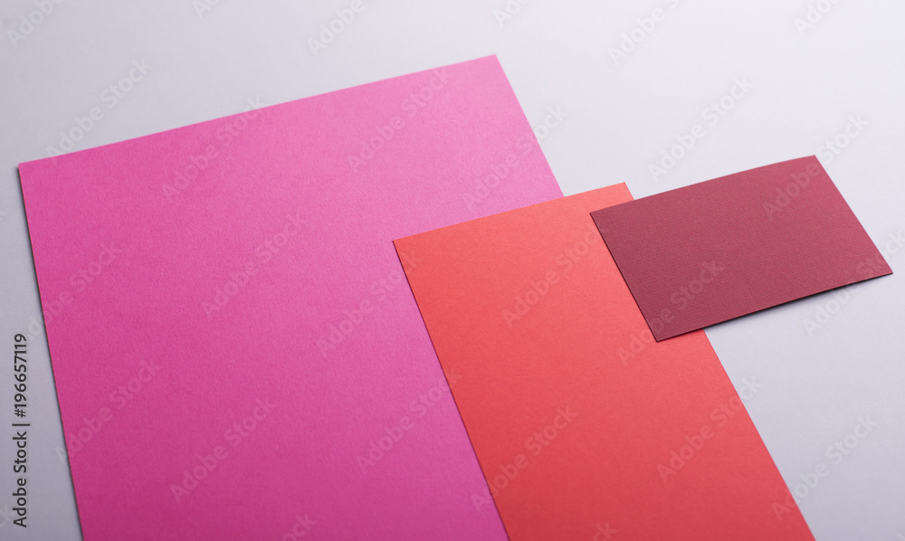 Cardboards of various colors next to business card of red color on gray background. Mockup. Cardboards of various colors next to business card of red color on gray background. Mockup.