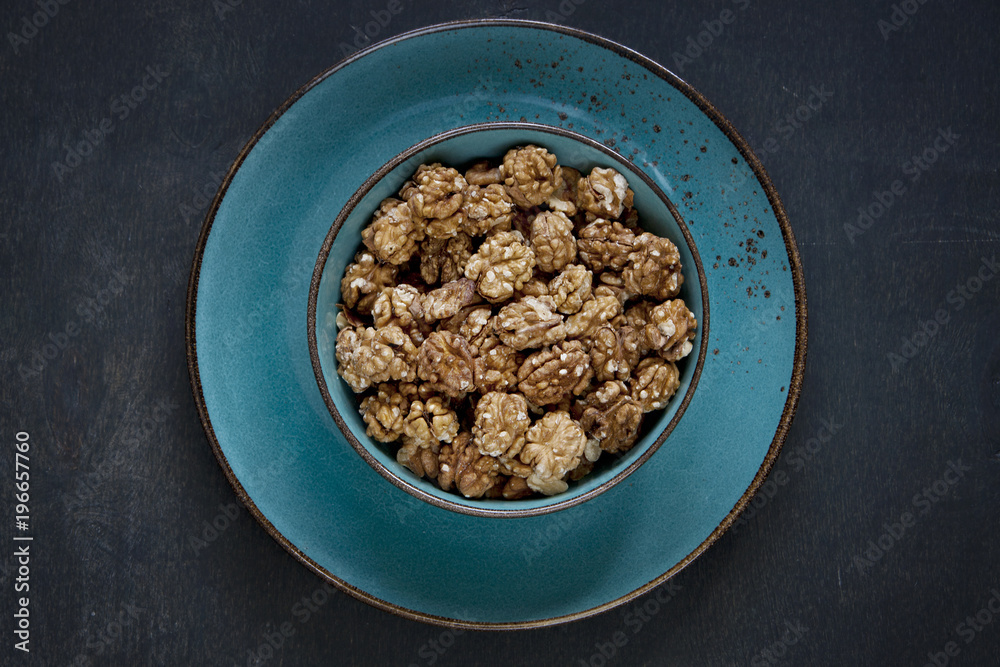 Close-up of a bowl with walnuts on a vintage wooden background. Top view, background.