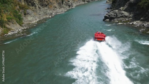 Red jet boat speeding down an alpine river. photo