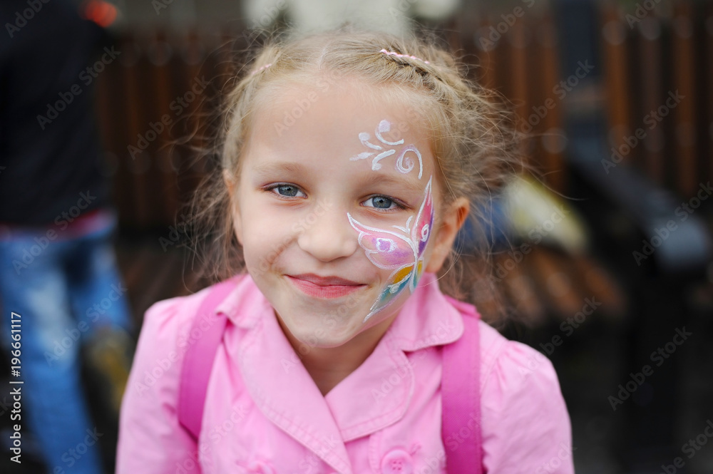 Young girl blonde with pigtails. She has a painted butterfly on her face Young girl blonde with pigtails. She has a painted butterfly on her face