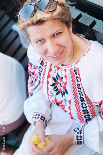 Woman in an embroidered Ukrainian shirt resting in the bench after dancing on a holiday in the summer