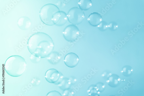 Abstract bright soap bubbles floating on a blue background.