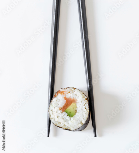 Sushi roll in black chopsticks isolated on white background. Japanese cuisine