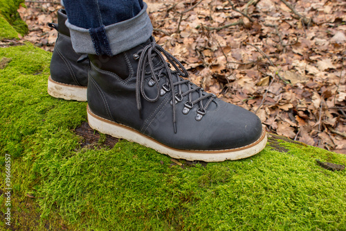 Hiking boots on a tree and green moss in the autumn
